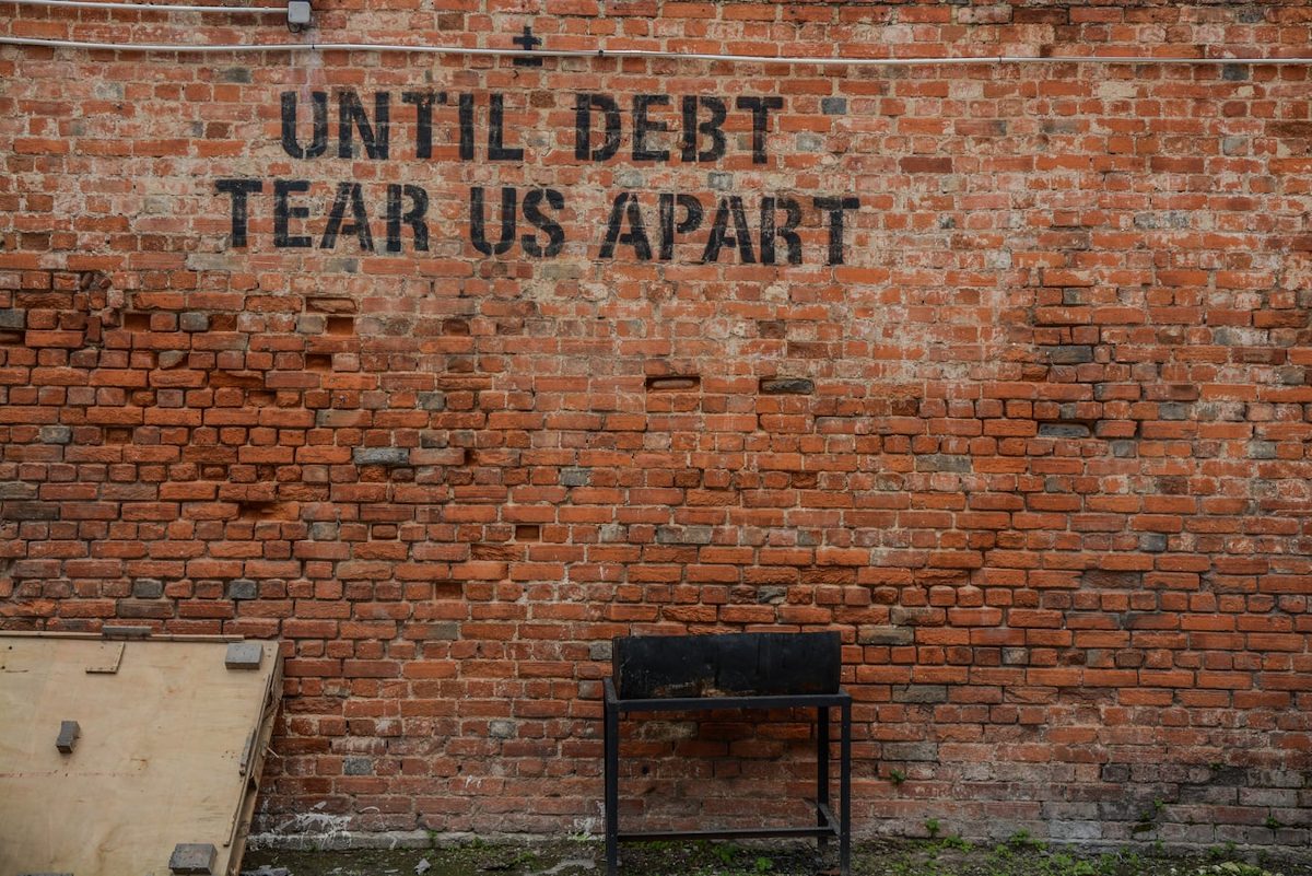 Until debt tear us apart written on a brick wall